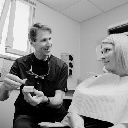 Dr. Almoney holding dentures and speaking to patient