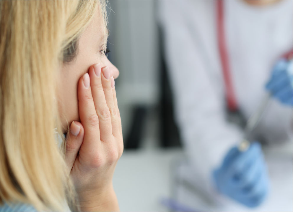 woman with a dental emergency holding her cheek.