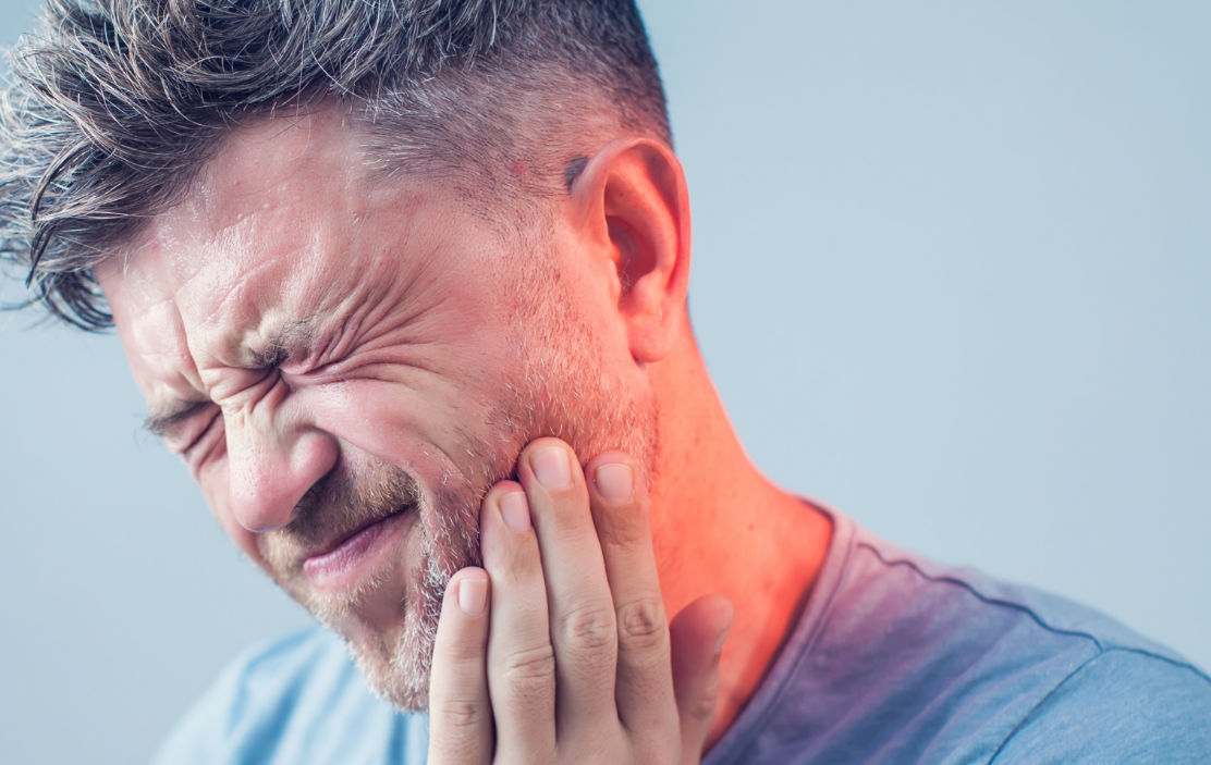 Man in dental pain holding his cheek