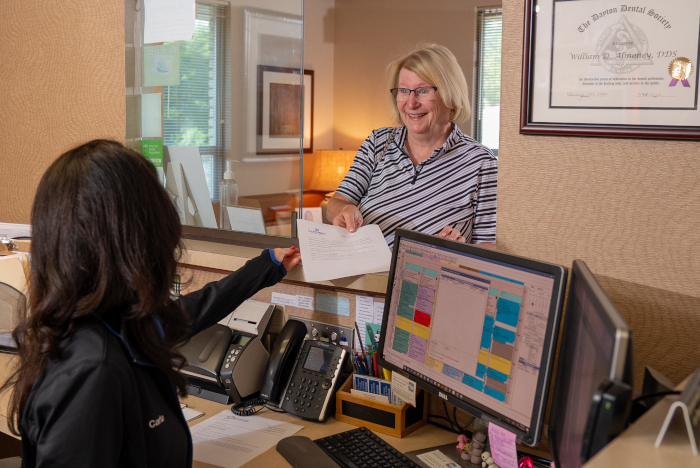 dental receptionist with a female patient at the front desk