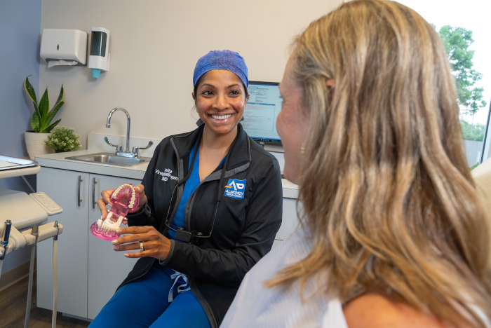 Asita Vinayagalingam, DMD, “Dr. V.” with a dental patient showing a model of teeth