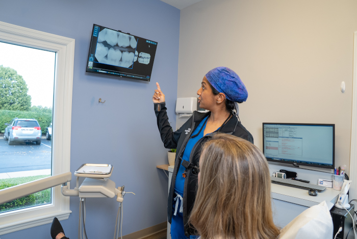 Dr. Asita Vinayagalingam, Dr. V. with a patient pointing a an X-Ray image