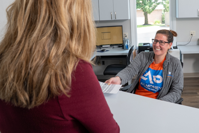 front desk assistant smiling with a female dental patient.